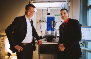 Prof. Frank Mücklich (links) und Prof. Andrés F. Lasagni (rechts) vor einer am Fraunhofer IWS entwickelten DLIP µFAB-Anlage