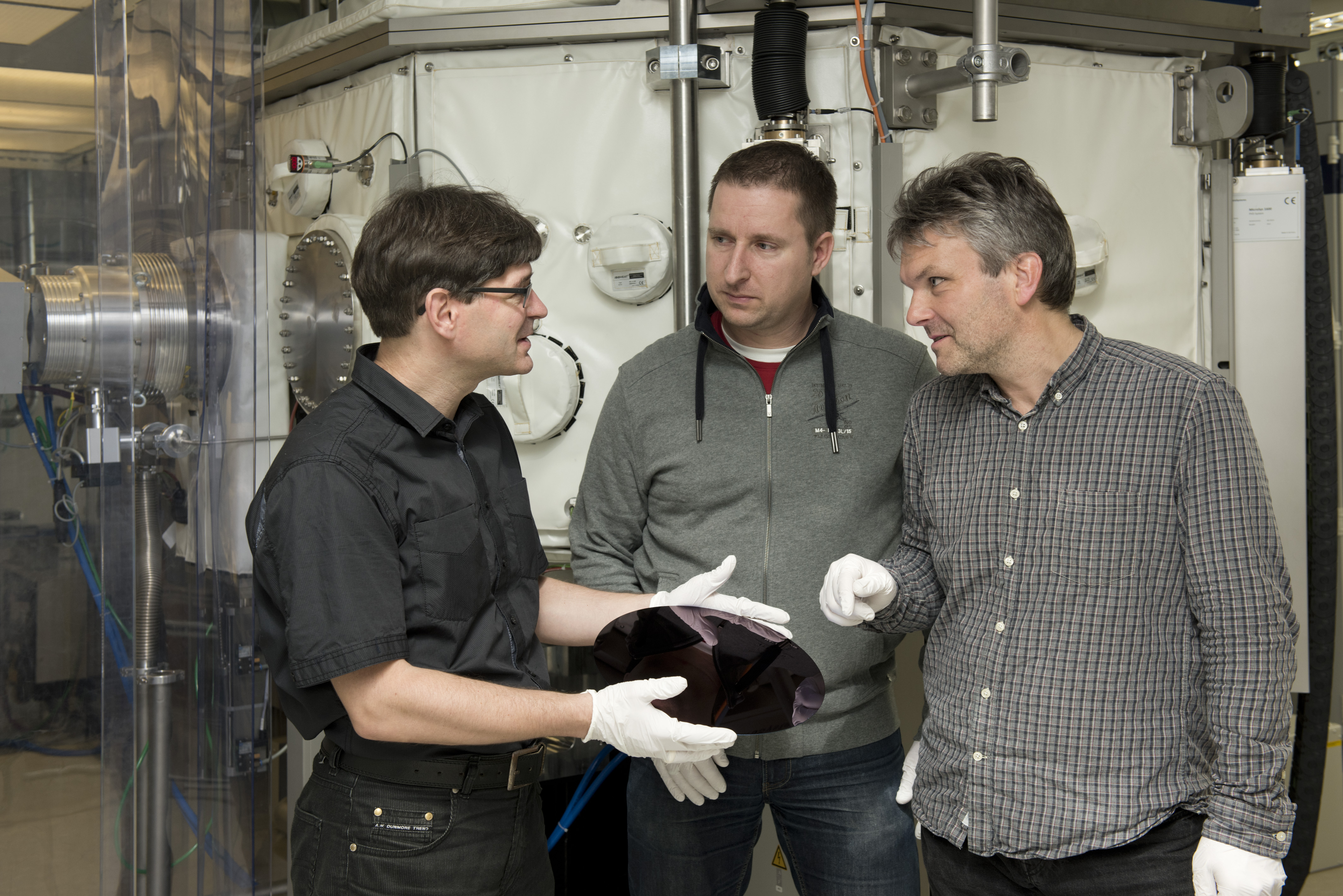 Dr. Stefan Braun, Maik Menzel and Peter Gawlitza (f.l.t.r.) in front of the coating device for the development of EUV reflection layers