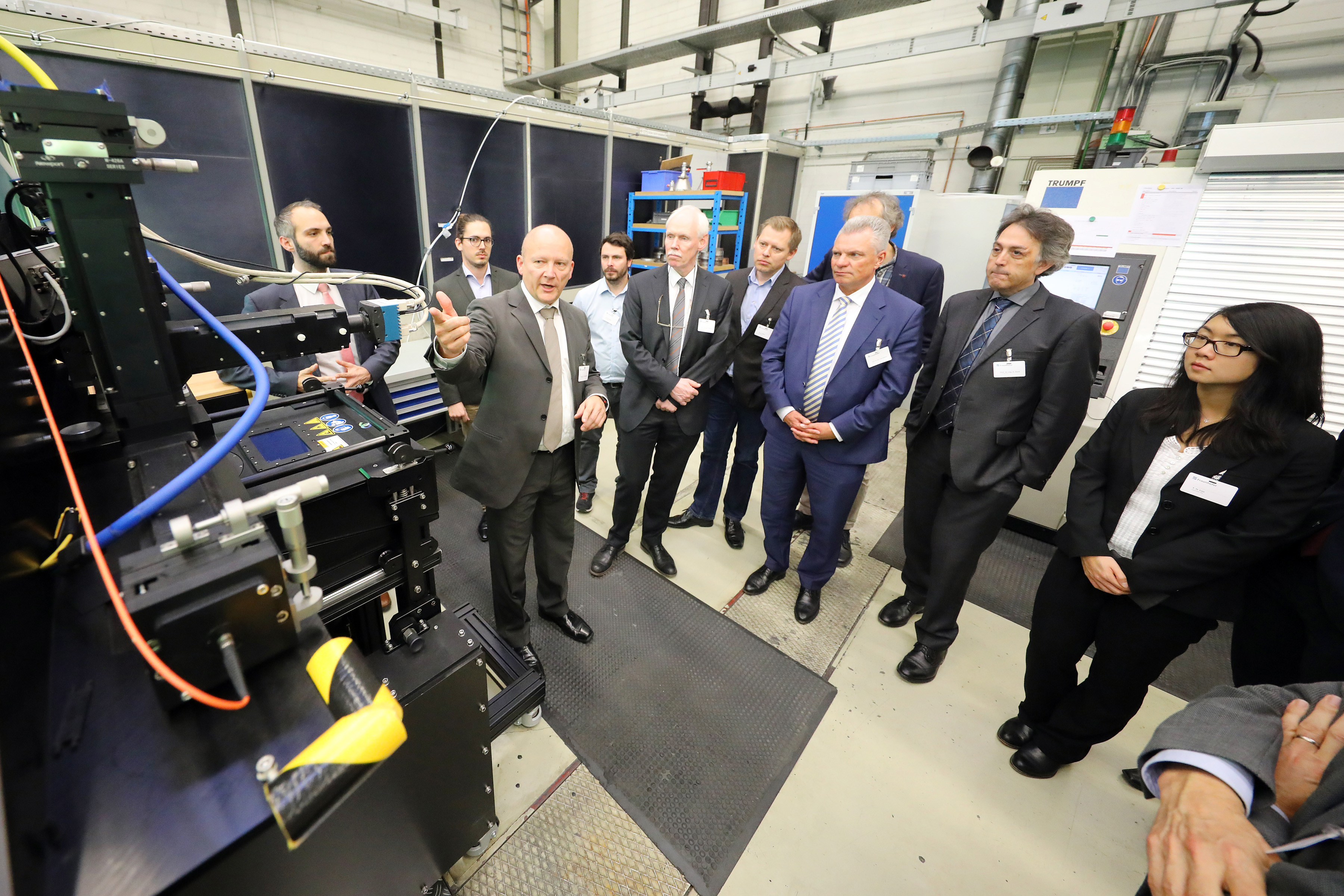Participants of the futureAM kick-off meeting at the laboratory tour at the Fraunhofer ILT. Ulrich Thombansen explains the system technology for selective laser melting.